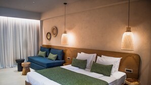 A modern bedroom with a large bed, a blue sofa, and two hanging pendant lights. - Panorama Hotel (Kissamos)