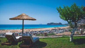 A beach view with lounge chairs and a thatched umbrella. - Panorama Hotel (Kissamos)