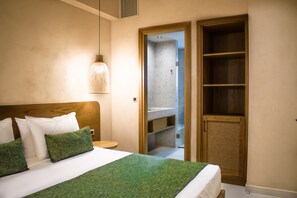 A hotel room with a bed, a nightstand, a wooden wardrobe, and a bathroom visible through an open door. - Panorama Hotel (Kissamos)