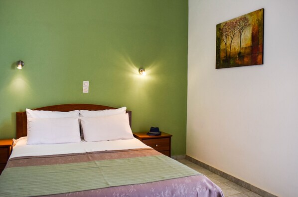 Una cama bien hecha con cabecera de madera, dos mesitas de noche y un cuadro colgado en la pared.