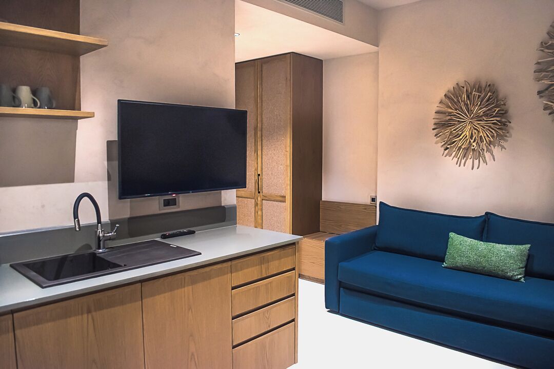 Una cocina moderna con televisor integrado, armarios de madera y un sofá azul.
