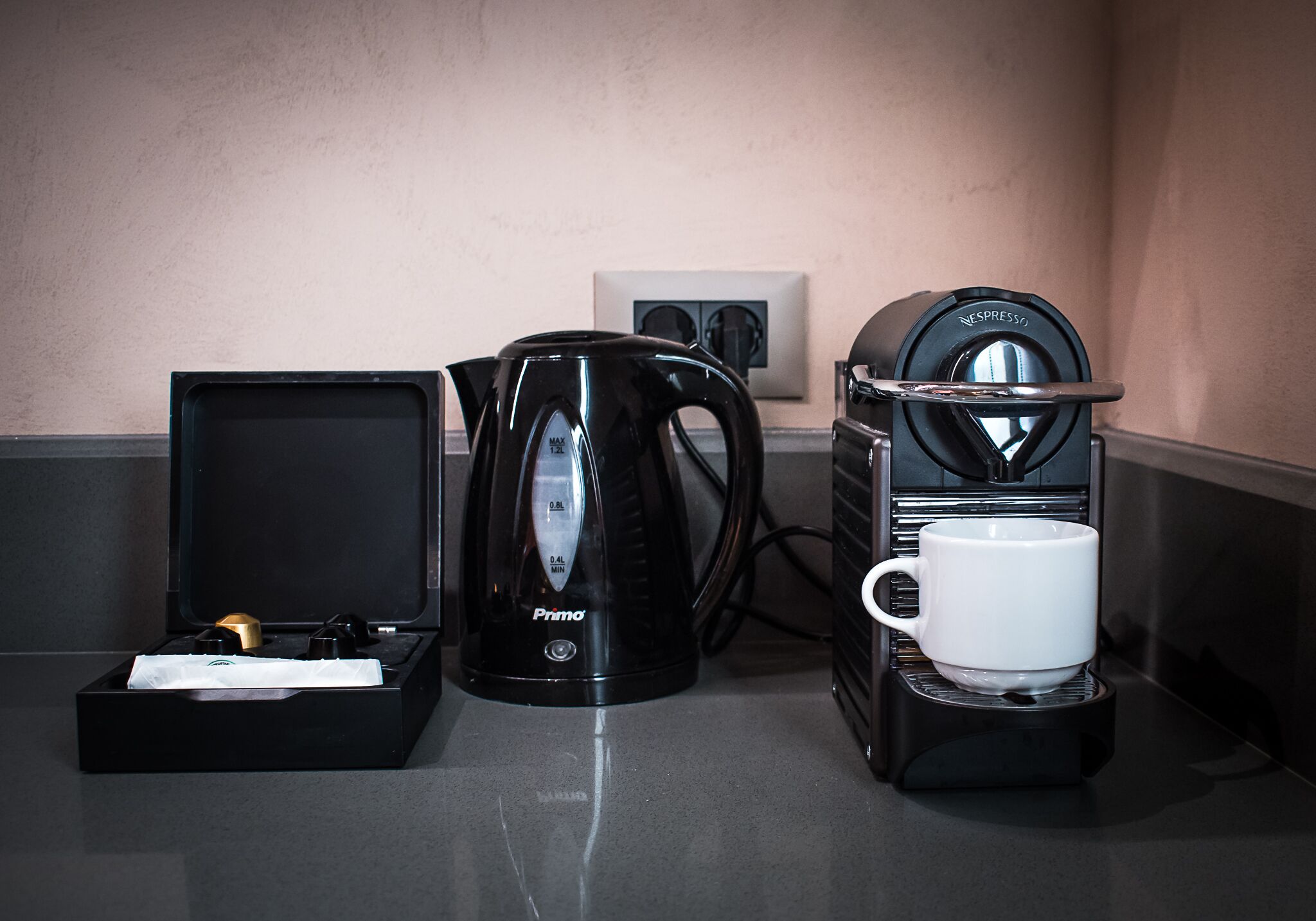 A coffee maker, a kettle, and a cup on a countertop.