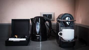 A coffee maker, a kettle, and a cup on a countertop.