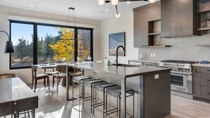 Een moderne keuken met een groot eiland, barkrukken en uitzicht op de omgeving.