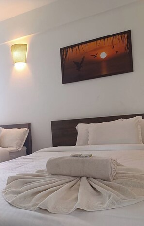Una habitación de hotel con una cama, un cuadro colgado en la pared y una lámpara de pared.