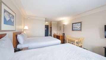 Habitación de hotel con dos camas, un escritorio, una silla, una lámpara y un televisor.