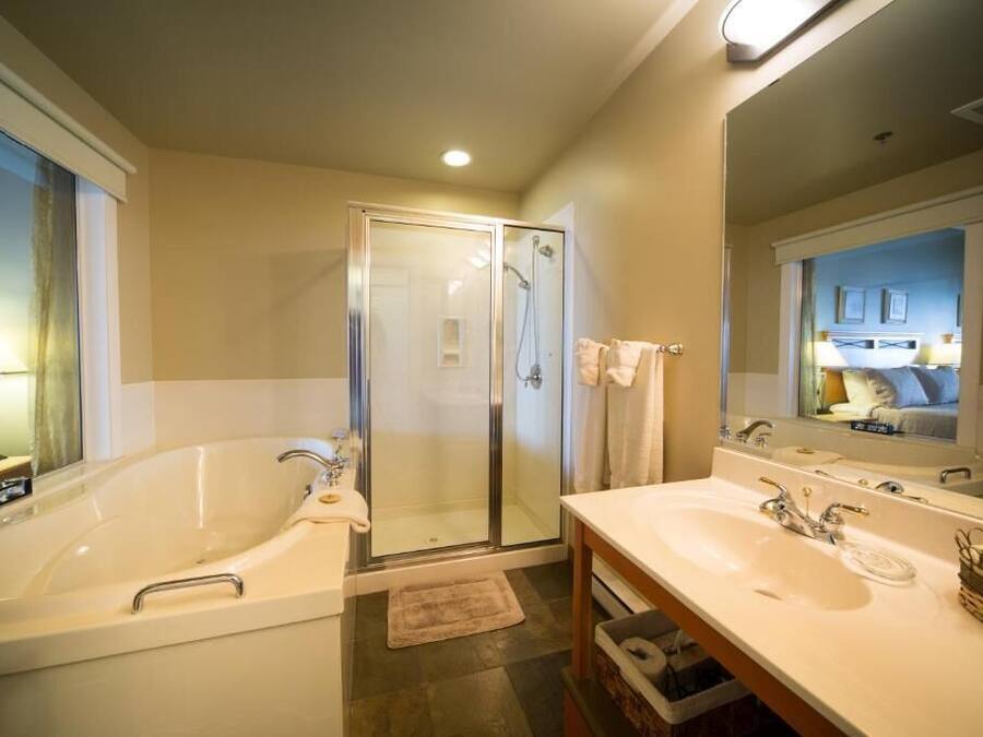 A modern bathroom with a large bathtub, a walk-in shower, and a vanity with two sinks.