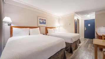 A hotel room with two beds, a desk, and a chair.
