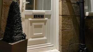 A white door with a grid pattern window, a small Christmas tree, and the number 127 on the door. - COSY HLA HOLYTOWN APARTMENT (Bellshill)