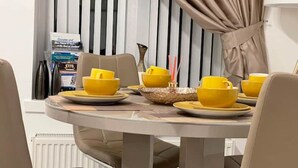 A dining area with a round table set for four, featuring yellow bowls and plates. - COSY HLA HOLYTOWN APARTMENT (Bellshill)