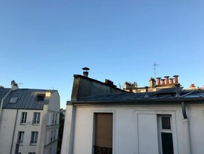 Urban residential building with a flat roof and multiple chimneys.
