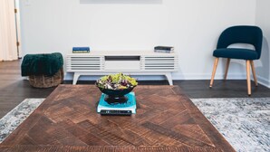Una sala moderna con una mesa de centro de madera, un tazón de ensalada, un control remoto y una estantería.