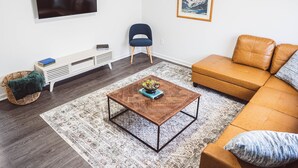 Una sala de estar moderna con un televisor de pantalla plana, un sofá, una mesa de centro y un cuadro en la pared.