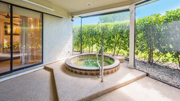 Zona de spa con jacuzzi, ventanas amplias y vistas a la vegetación.