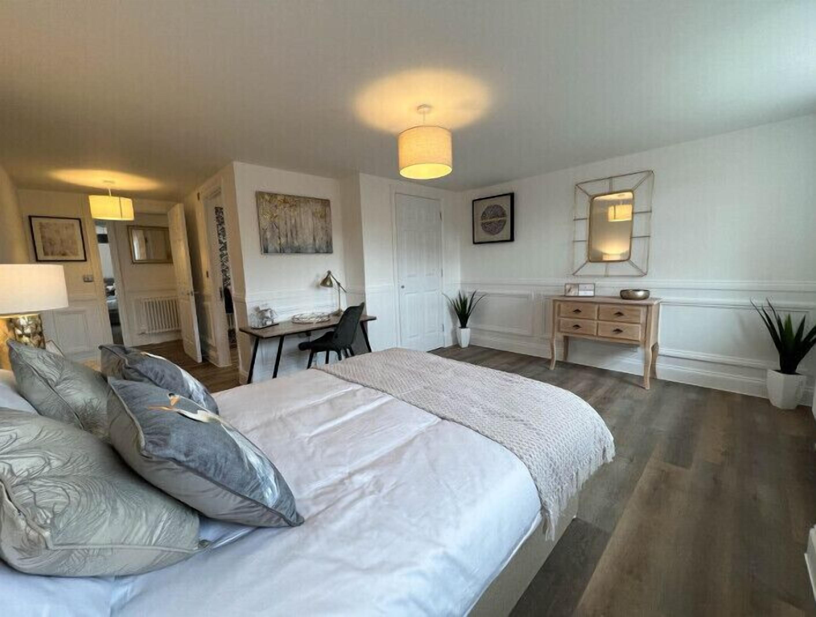 A bedroom with a large bed, a desk, and a dresser.