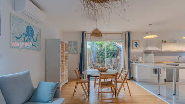 A modern kitchen with a dining area, featuring a round table, wooden chairs, and a hanging light fixture. - La Terrasse - Three Bedroom House, Sleeps 6 (La Teste-de-Buch)
