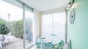 A dining area with a table set for two, a sliding glass door leading to an outdoor patio, and a wall-mounted clock.