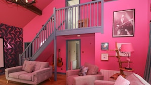 A pink-themed living room with two sofas, a staircase, a guitar, and a framed picture on the wall. - Holmere Bank (Carnforth)