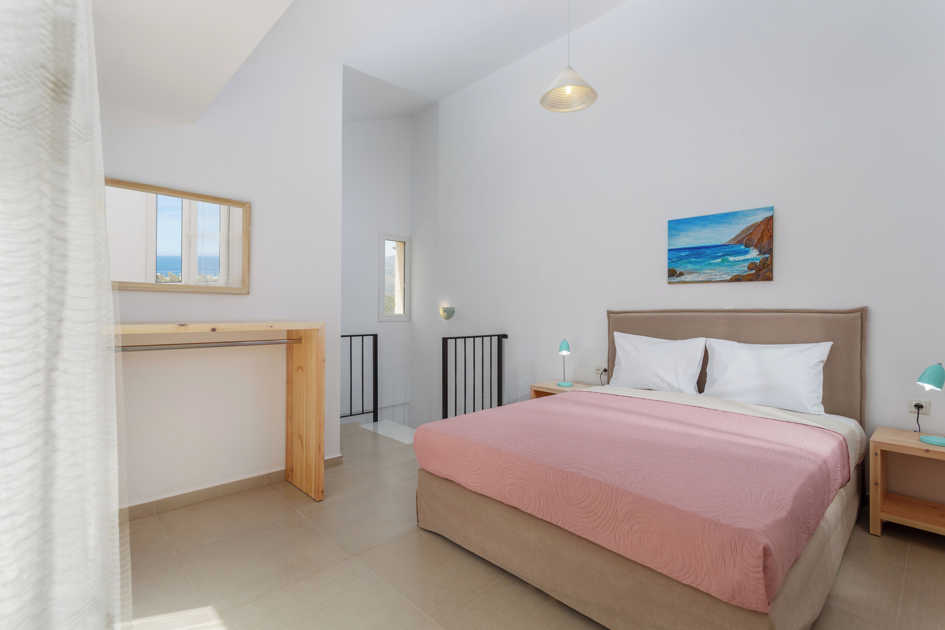 A bedroom with a bed, bedside tables, a nightstand, a painting, and a window.