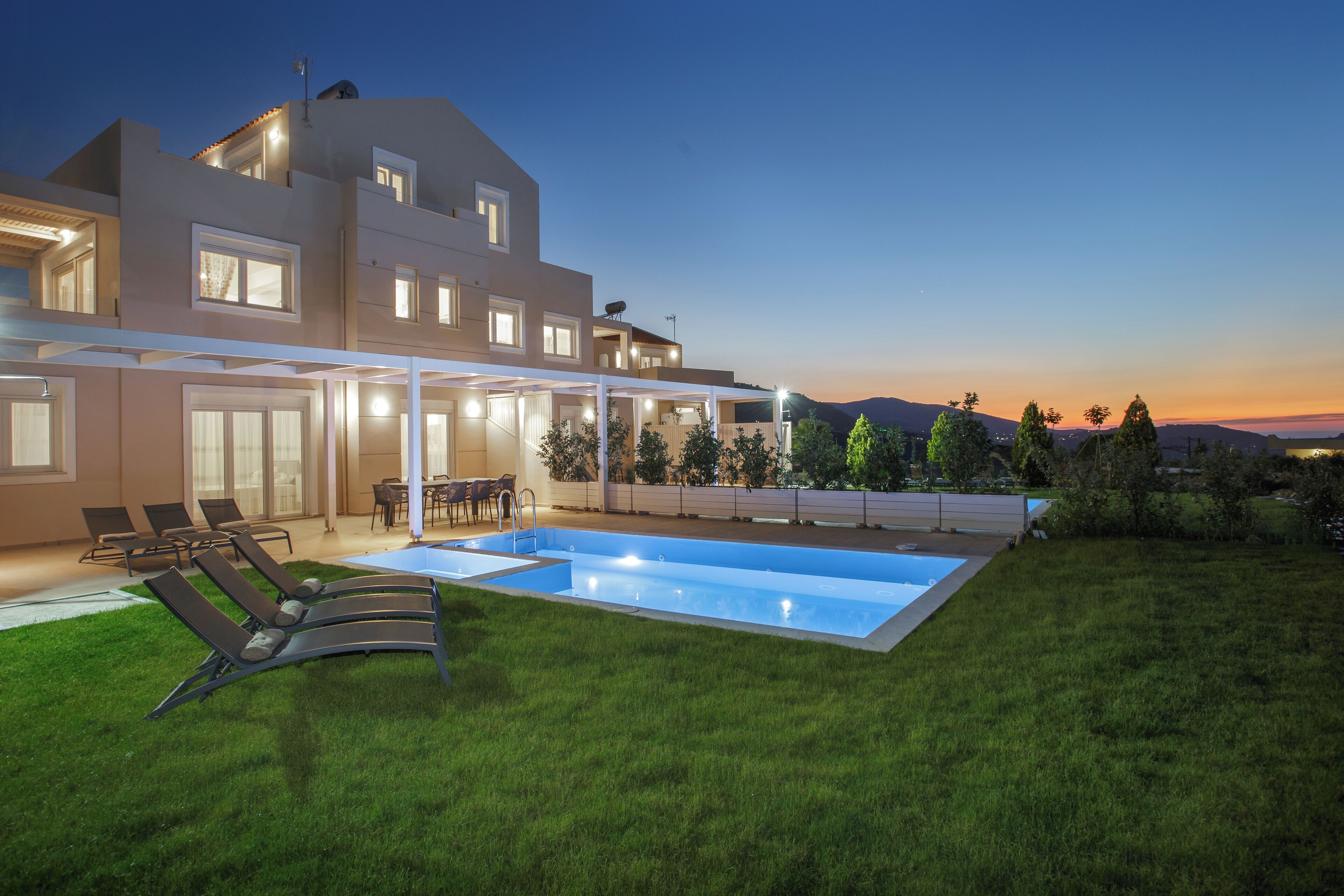 A modern house with a swimming pool, outdoor seating, and a well-maintained lawn.