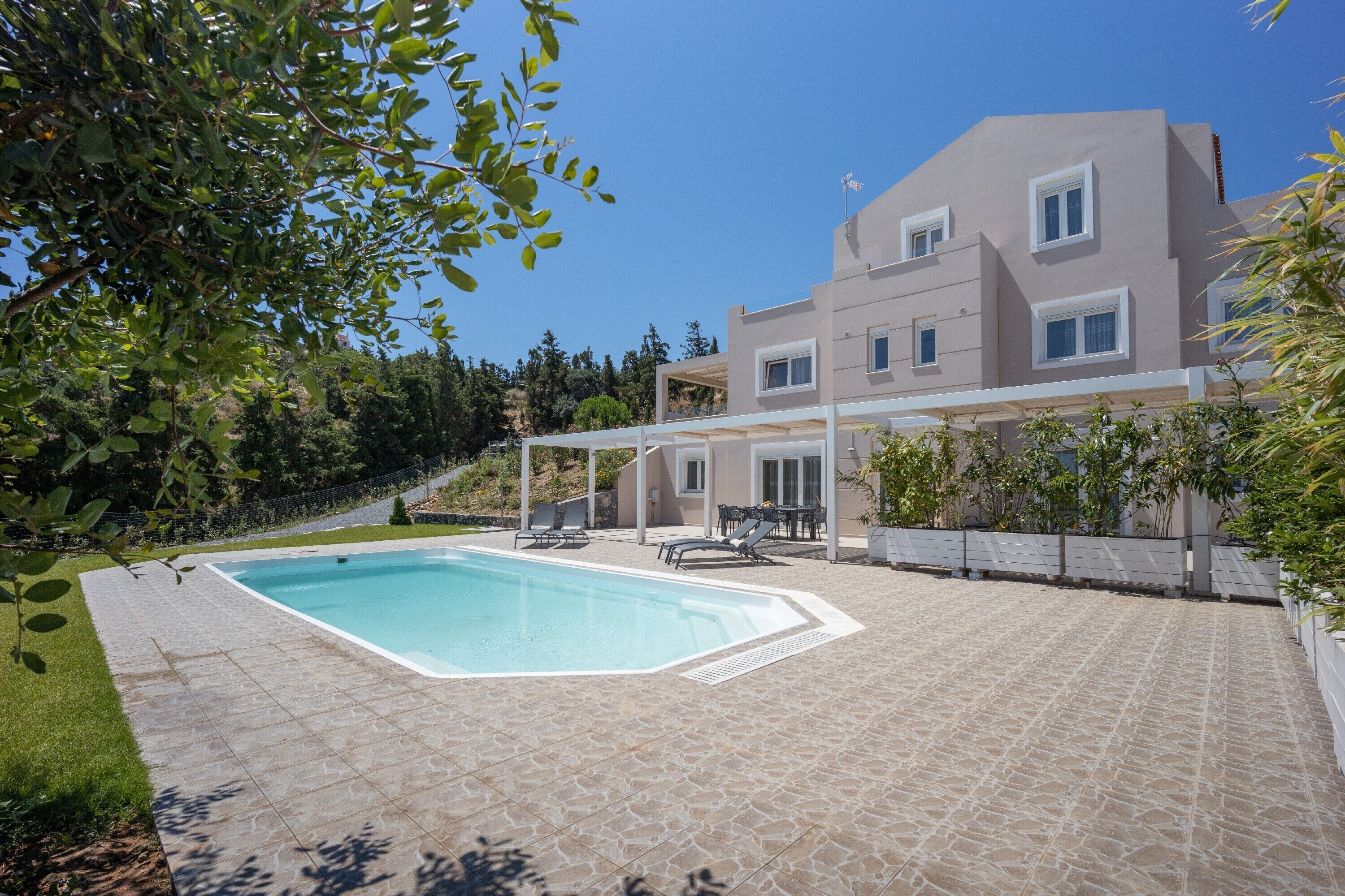 A modern two-story house with a swimming pool, outdoor seating, and a covered patio area.