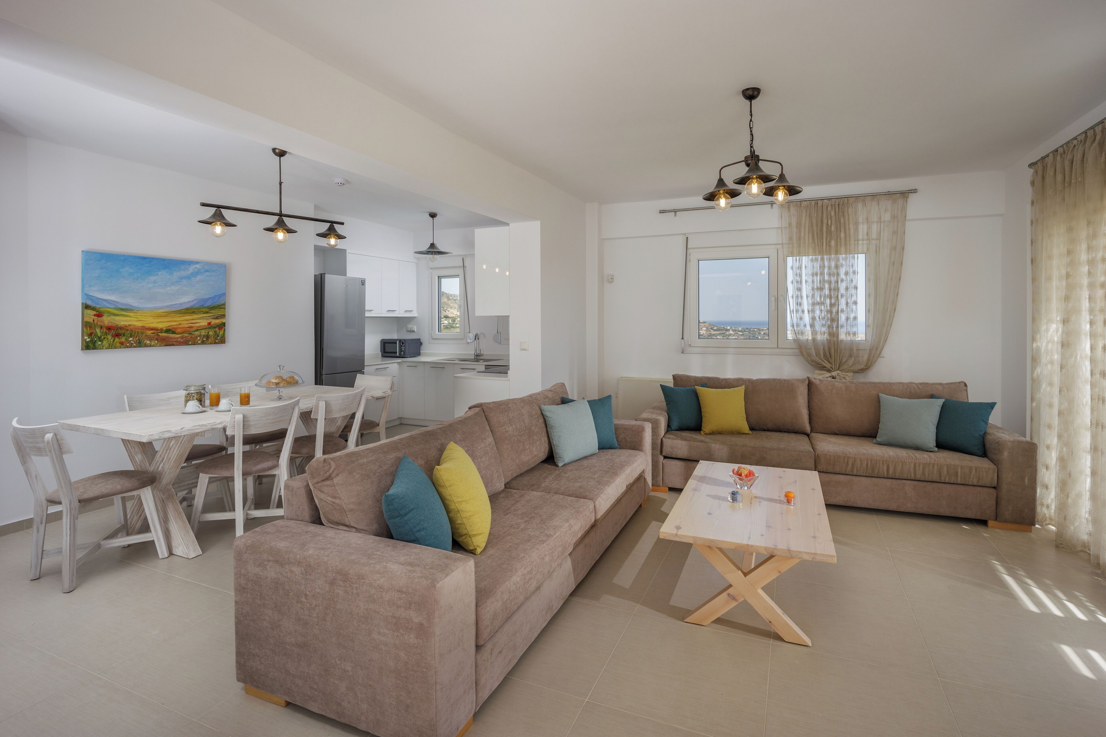 A modern living room with a beige sofa, a wooden coffee table, and a dining area with a white table and chairs.