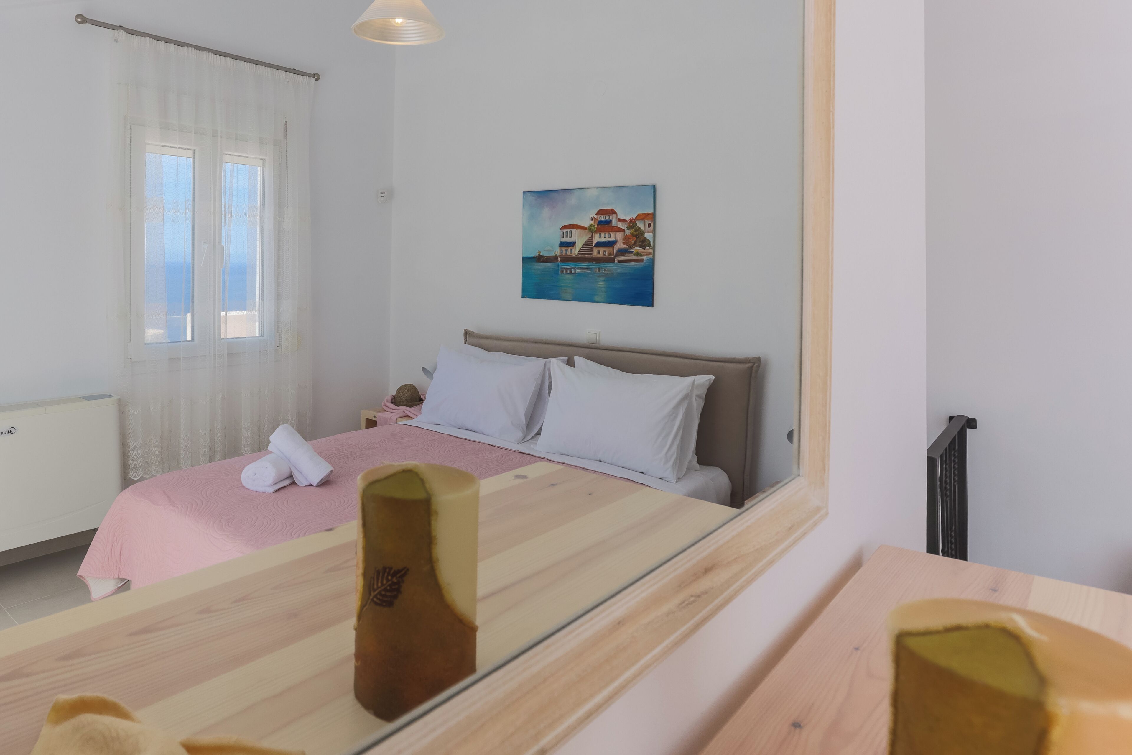 A hotel room with a bed, a window with curtains, a painting on the wall, and a radiator.