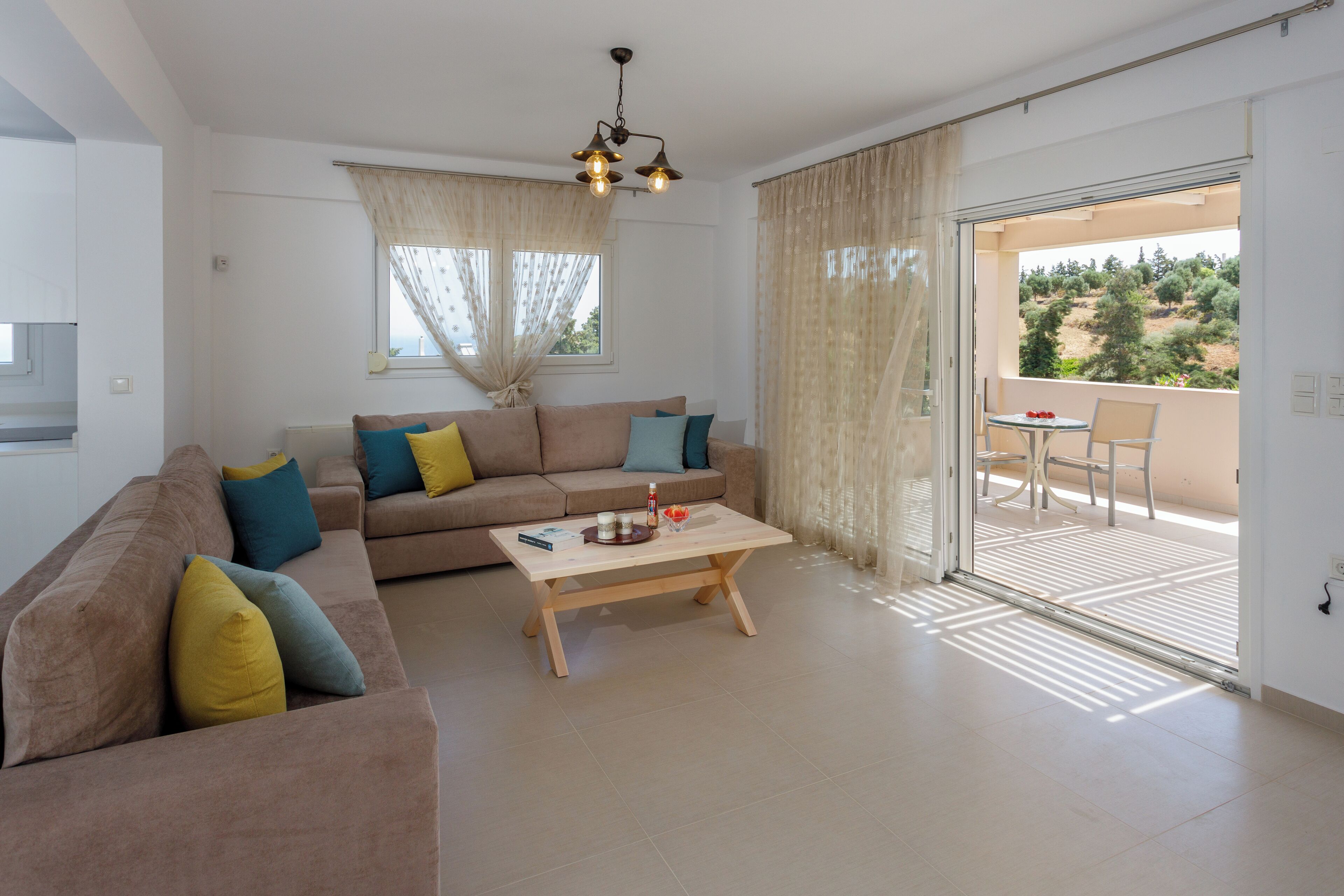 A modern living room with a sofa, coffee table, and a balcony with a table and chairs.