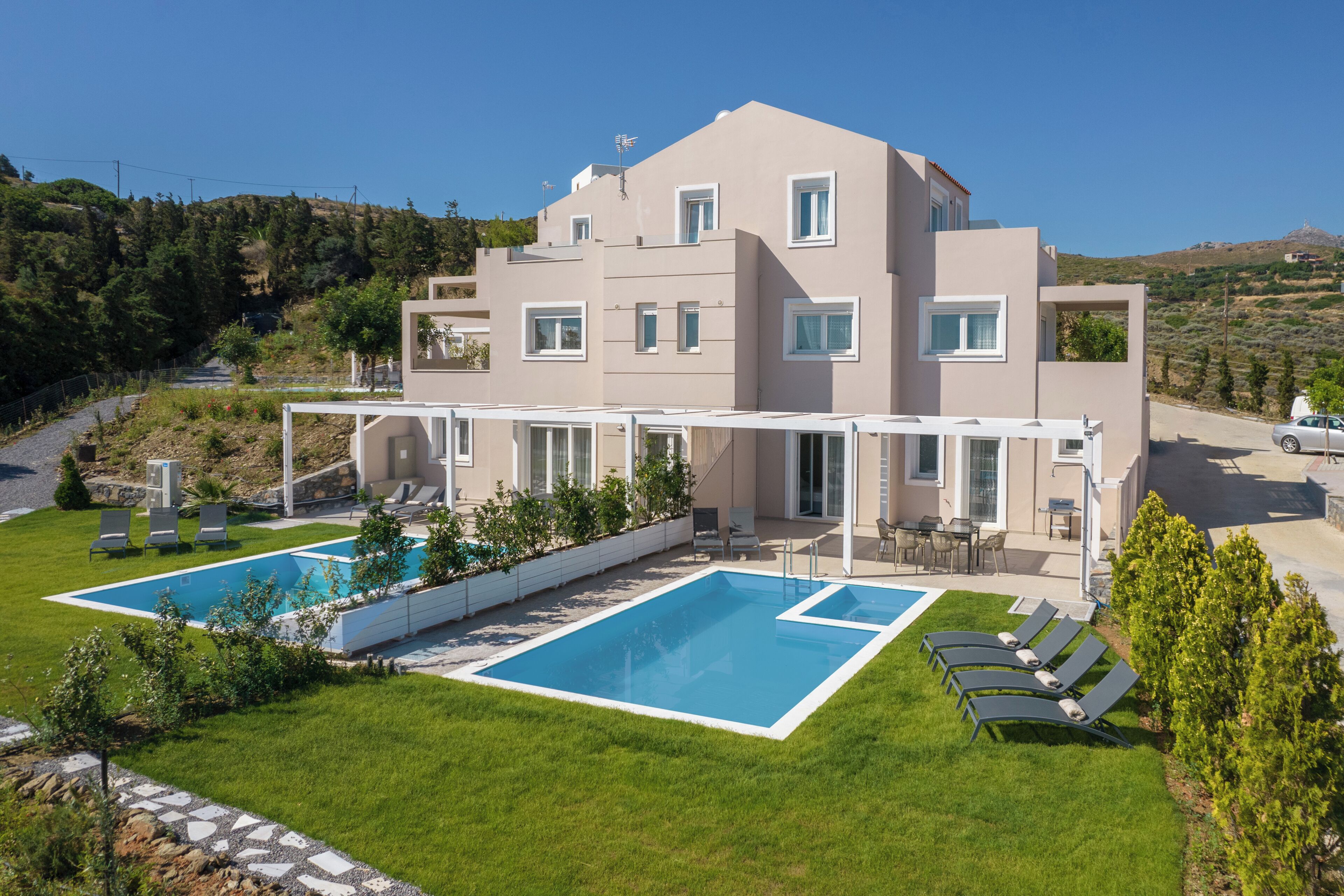 Une maison moderne à deux étages, dotée d’une piscine et d’un espace extérieur aménagé pour se détendre.
