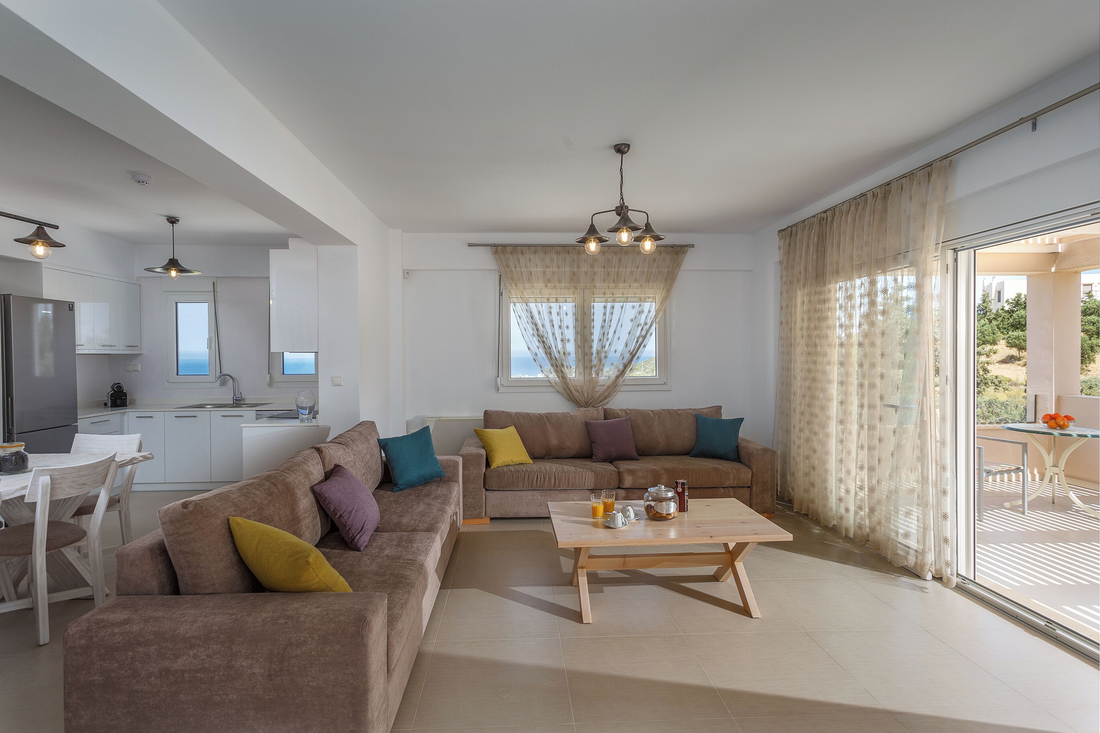 A modern living room with a sofa set, a wooden coffee table, and a kitchen in the background.