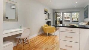 A modern kitchen with white cabinetry, a wooden floor, and a yellow chair.