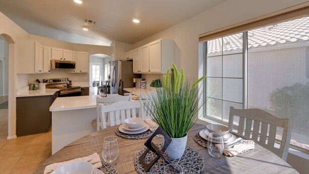 A modern kitchen with white cabinetry, a central island, and a dining area with a table set for two.