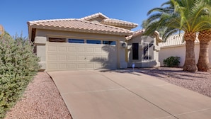 A residential house with a garage, a driveway, and a palm tree.