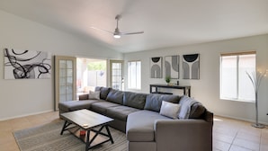 A modern living room with a sectional sofa, a coffee table, and a ceiling fan.