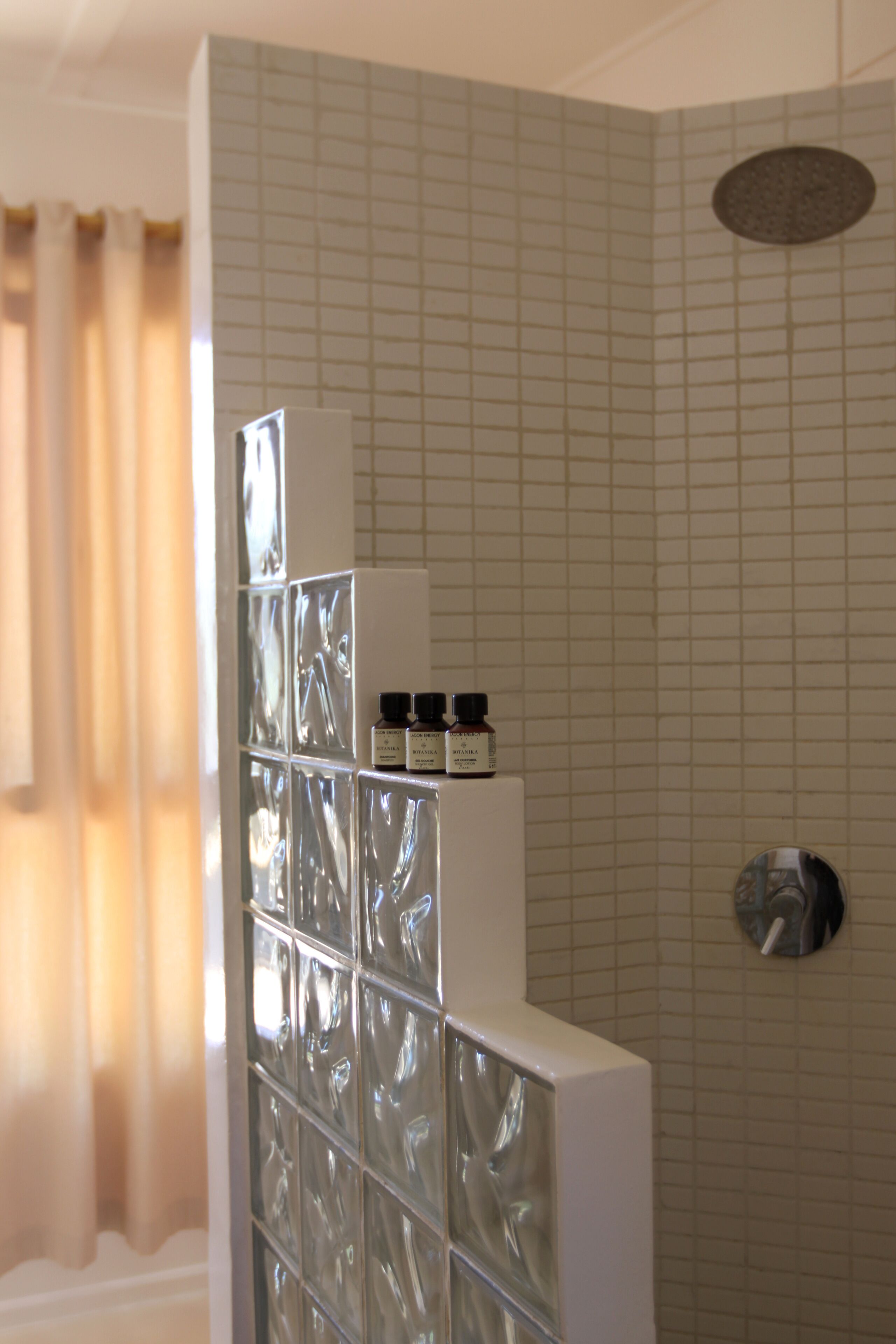 A bathroom with a glass shower enclosure, a white sink, and a mirror.