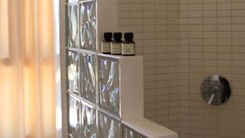 A bathroom with a glass shower enclosure, a white sink, and a mirror.