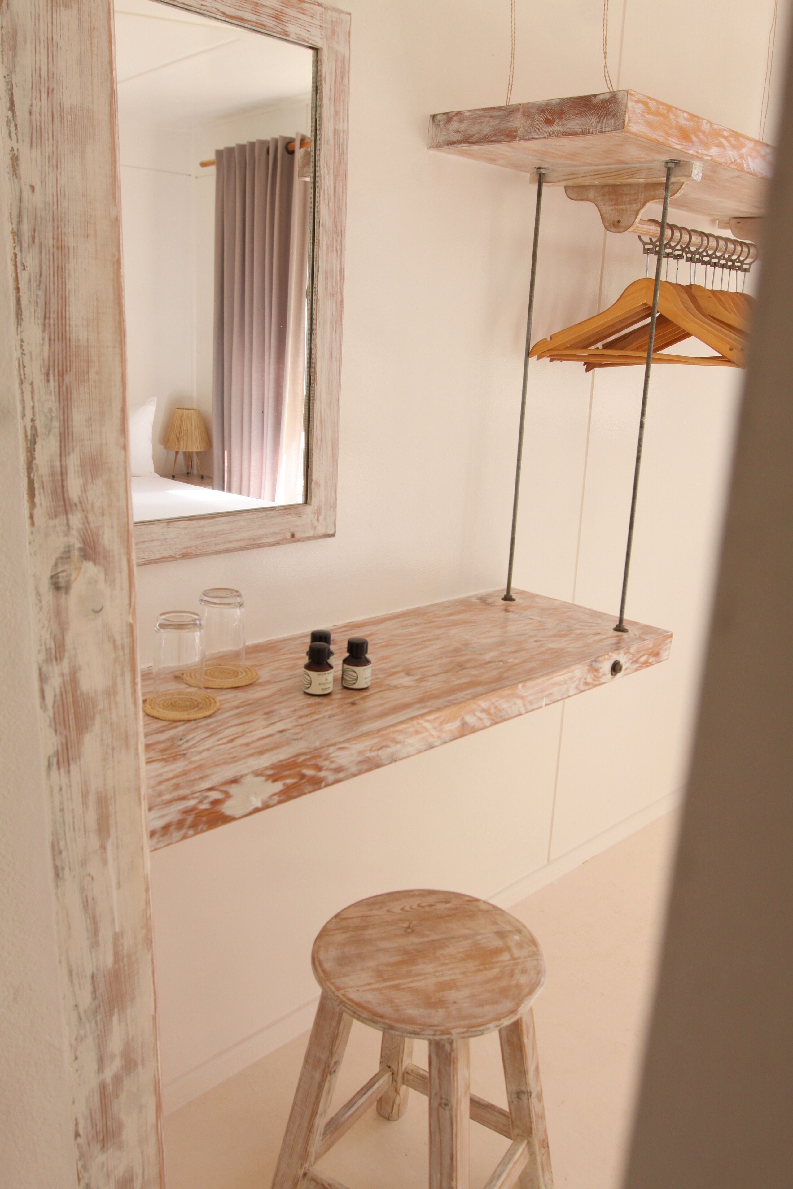 A bathroom with a wooden vanity, a hanging wooden rack, and a stool.