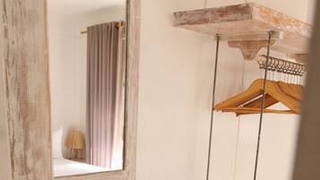A bathroom with a wooden vanity, a hanging wooden rack, and a stool.