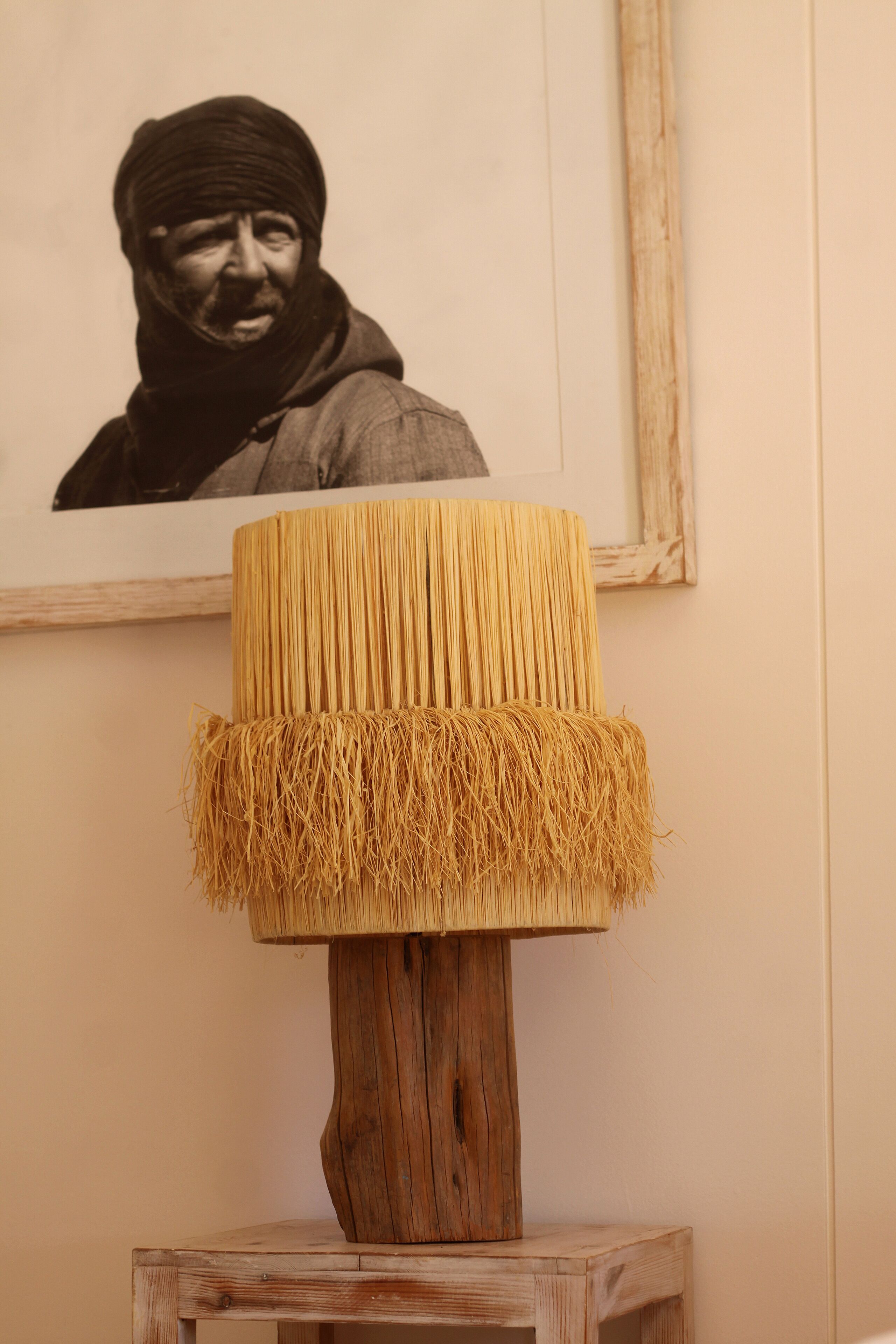A wooden table with a woven lamp on top.