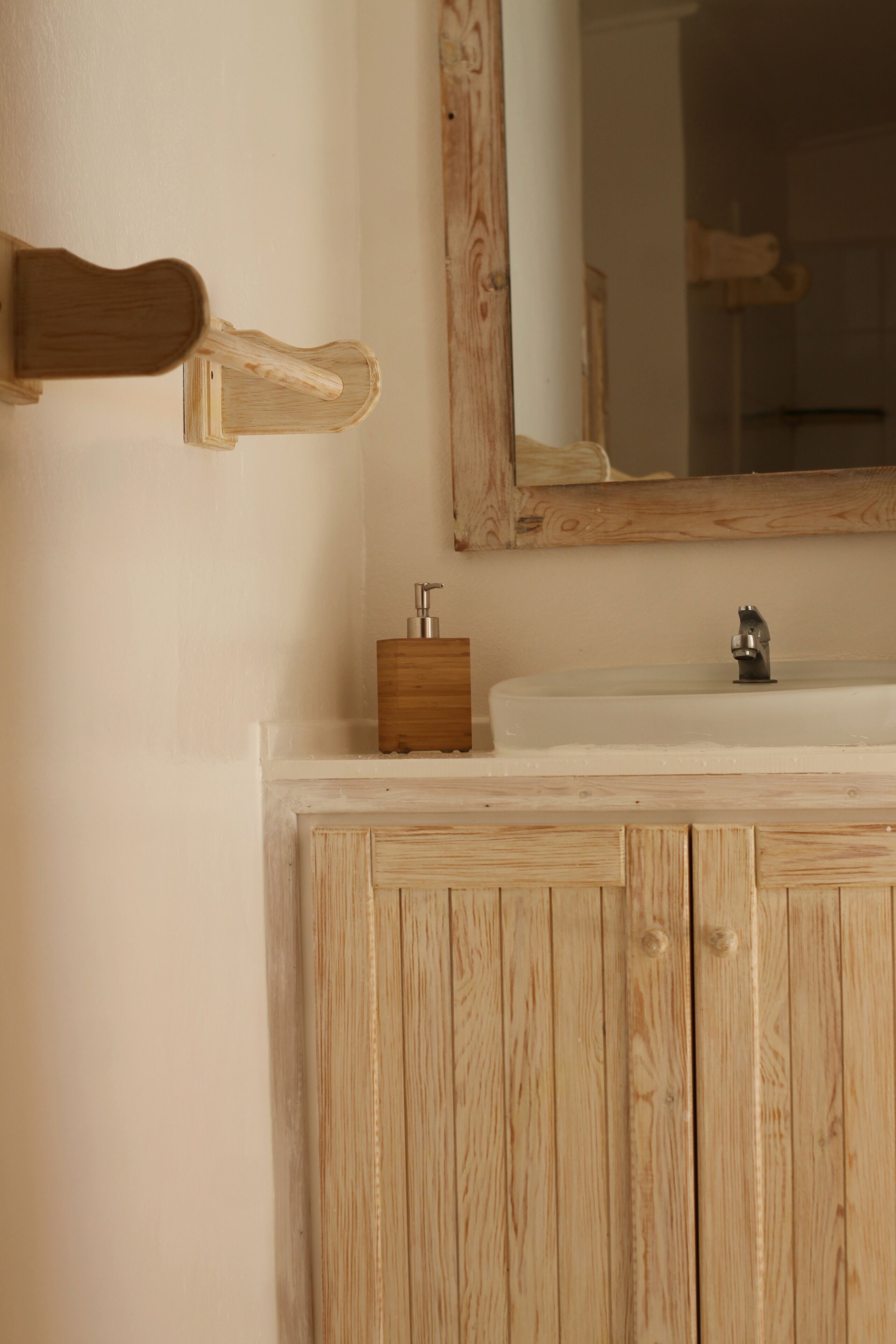A wooden vanity with a mirror and a sink.