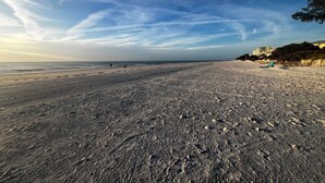 A beach with a clear sky, a sandy shore, and a few buildings in the background. - Relaxing Clearwater-St Pete Beaches!! Clean, beachy and water sports!  (Indian Shores)