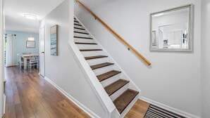A staircase with wooden steps and a white handrail, leading to a room with a large mirror and a framed picture on the wall. - Relaxing Clearwater-St Pete Beaches!! Clean, beachy and water sports!  (Indian Shores)