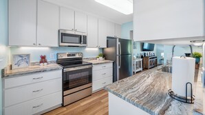 A modern kitchen with white cabinets, stainless steel appliances, and a marble countertop. - Relaxing Clearwater-St Pete Beaches!! Clean, beachy and water sports!  (Indian Shores)