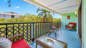 A balcony with wicker furniture, a glass table, and a red sofa. - Relaxing Clearwater-St Pete Beaches!! Clean, beachy and water sports!  (Indian Shores)