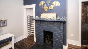 Une pièce avec un mur bleu foncé, une cheminée surmontée d’une inscription et une petite table sur laquelle est posé un cadre photo.