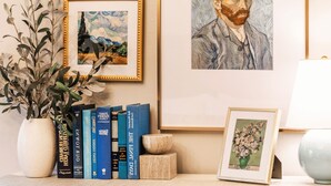 A bookshelf with books, a framed painting, and a vase with plants. - Cozy Downtown Retreat - Conference Center Home (Salt Lake City)
