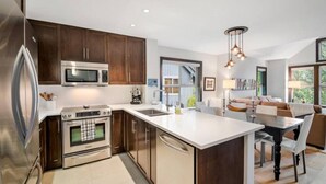 A modern kitchen with stainless steel appliances, a large island, and a dining area with a view.