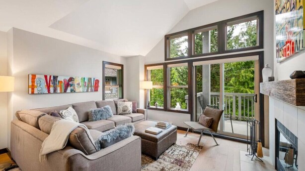 A spacious living room with a large window, a fireplace, and a modern sofa set.