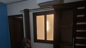A room with a closed door, a standing fan, and a window with light coming through. - Private room in very nice area. (Dakar)