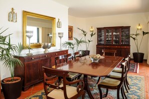 Ein Esszimmer mit Holztisch, Stühlen, einem Schrank und Topfpflanzen.